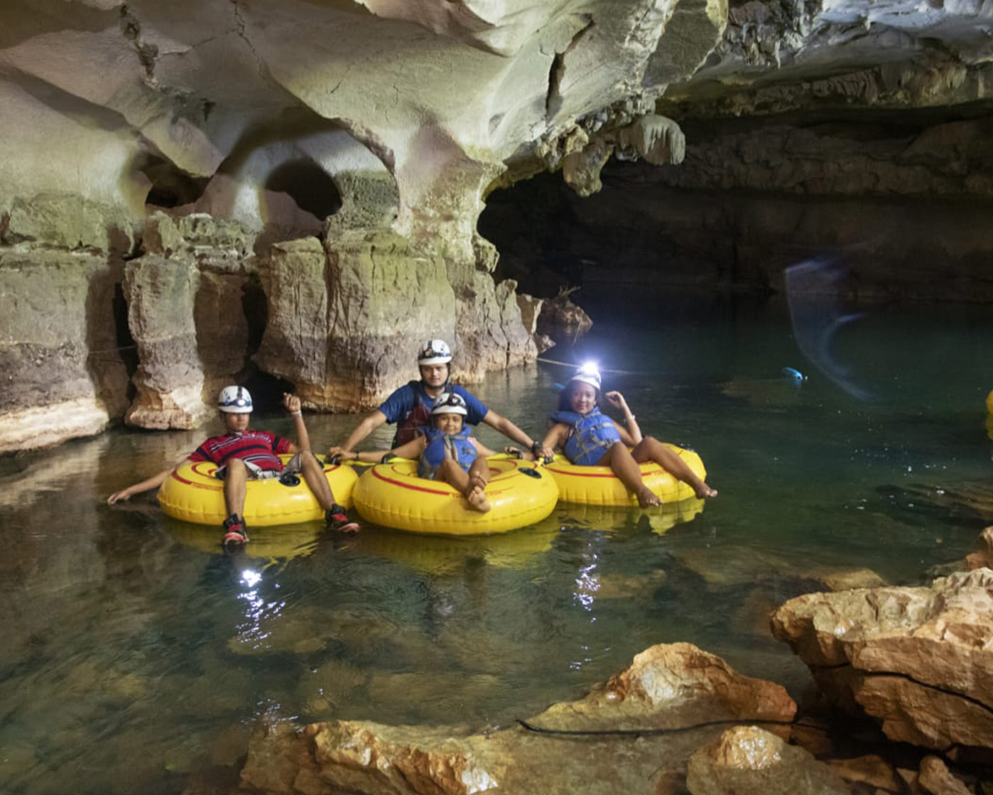 Image of a resort for sale in Belize, featuring a family having fun water tubing in a cave.